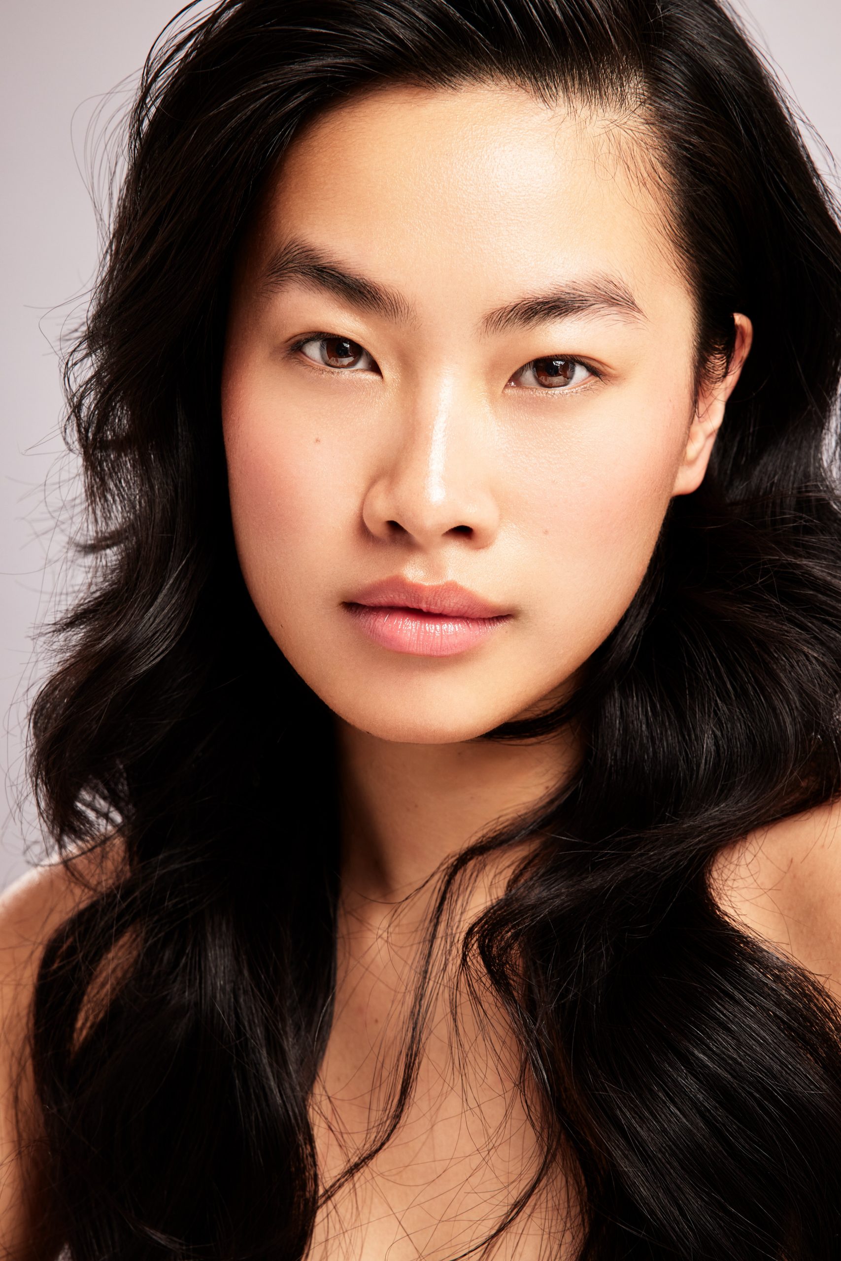 Natural beauty portrait, model with dark wavy hair and nude lip looking directly into camera, studio beauty photography by Furkan Ramadani