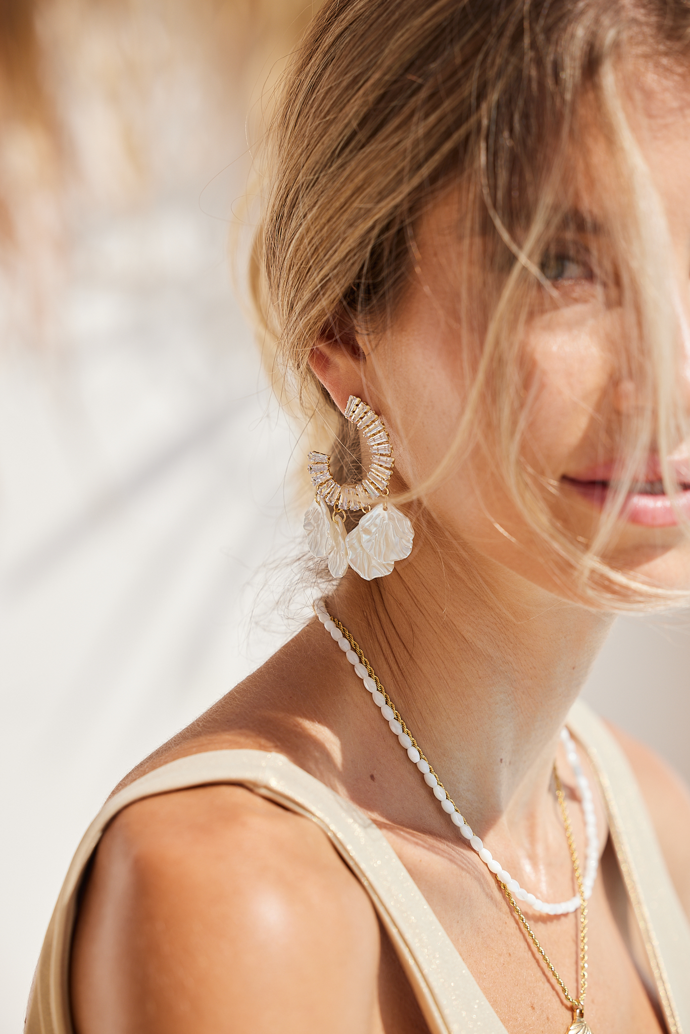Detail jewelry campaign shot, crystal and flower drop earring with layered gold and pearl necklaces on model, campaign photography by Furkan Ramadani for BeeGraced